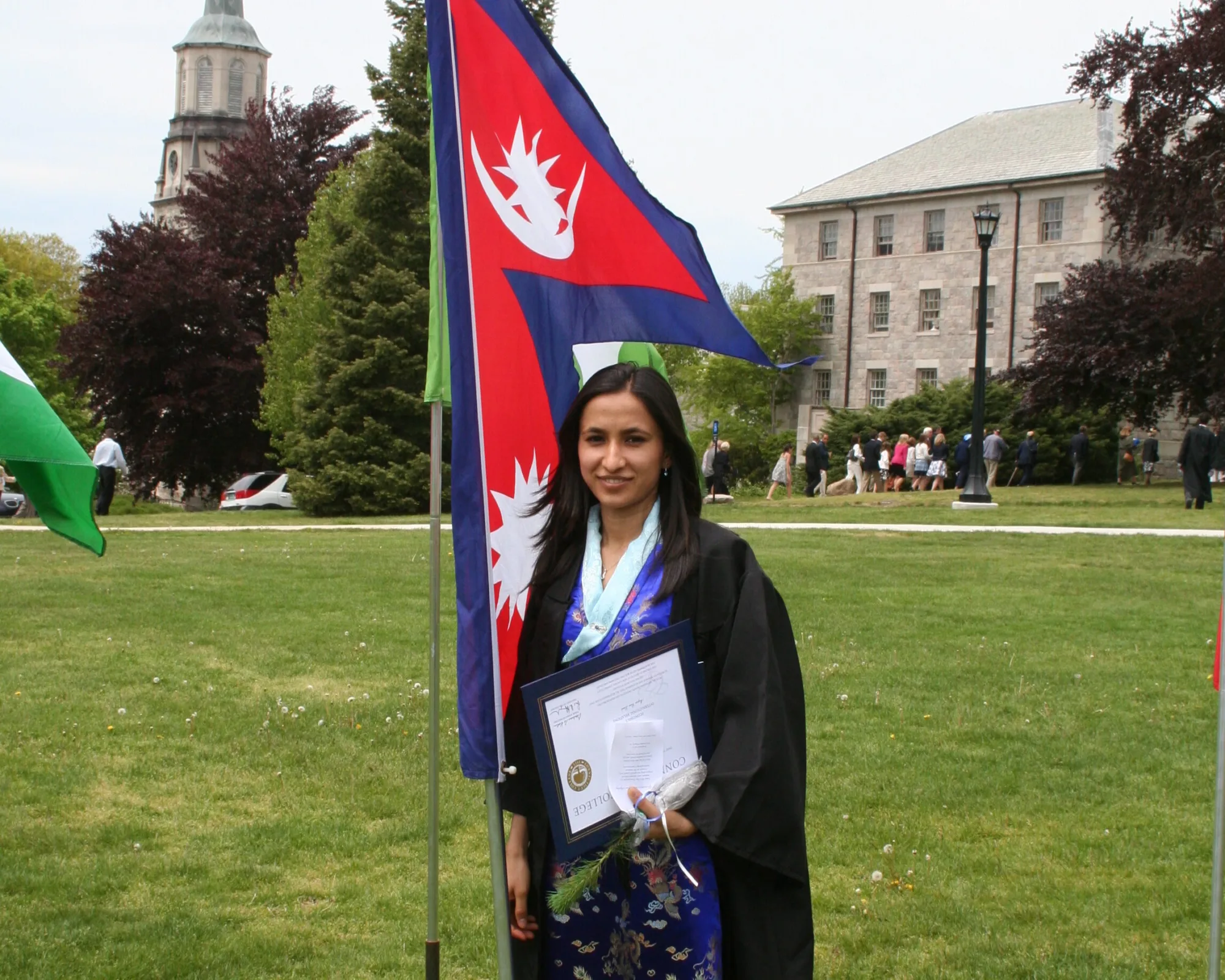 Pestalozzi International Nepal alumni Jyoti Pandey at the Connecticut college graduation. Wearing graduation uniform and standing in front of the Nepal flag.