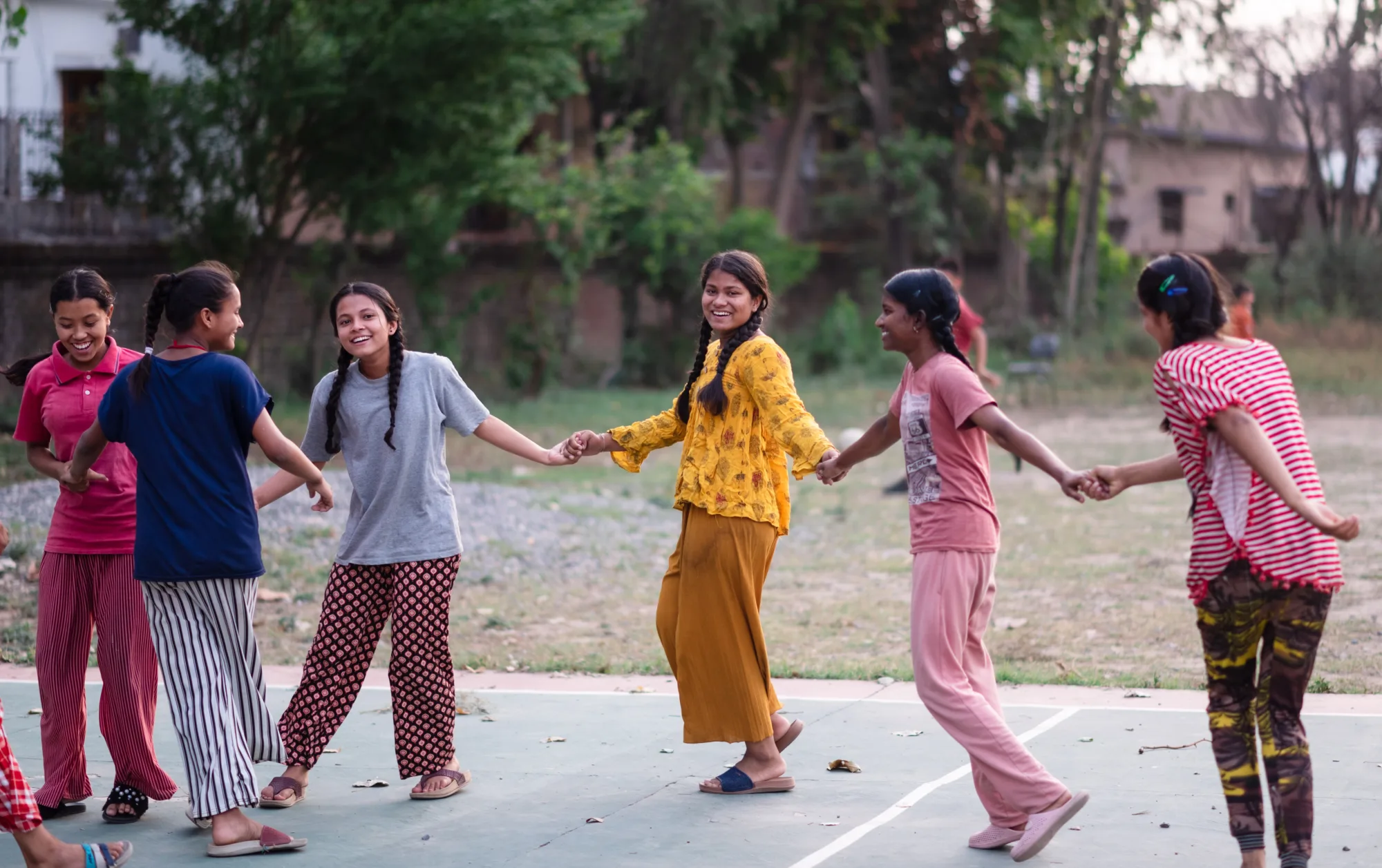 Six girls at Pestalozzi India holding hands forming a line and dancing