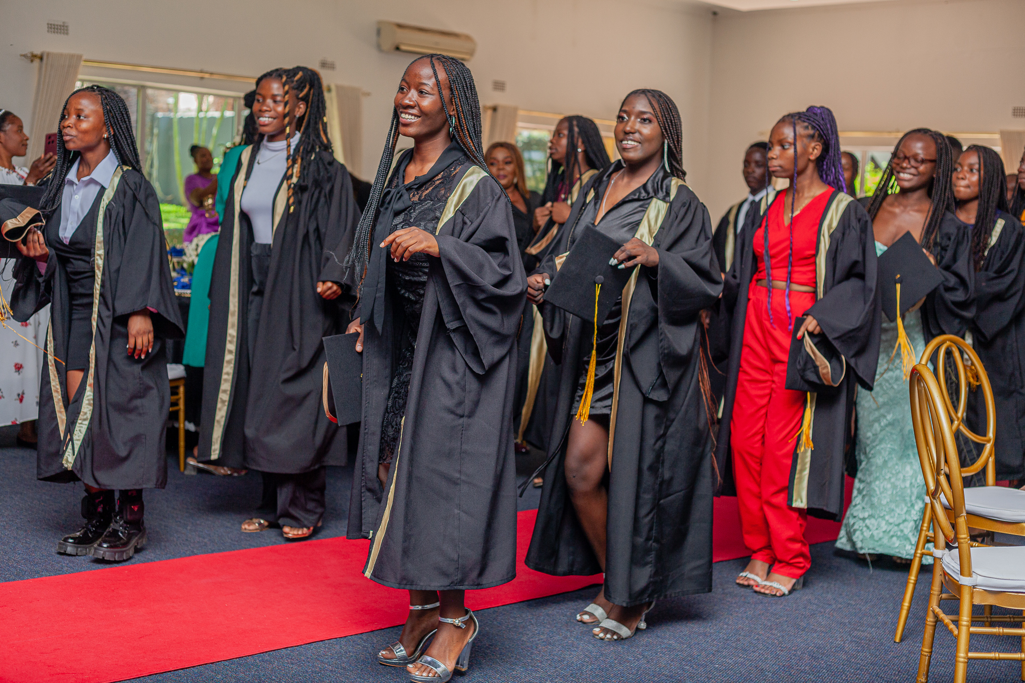Female Graduates in their Graduation uniform, celebrate, laugh and dance at the graduation ceremony of Pestalozzi International Zambia.
