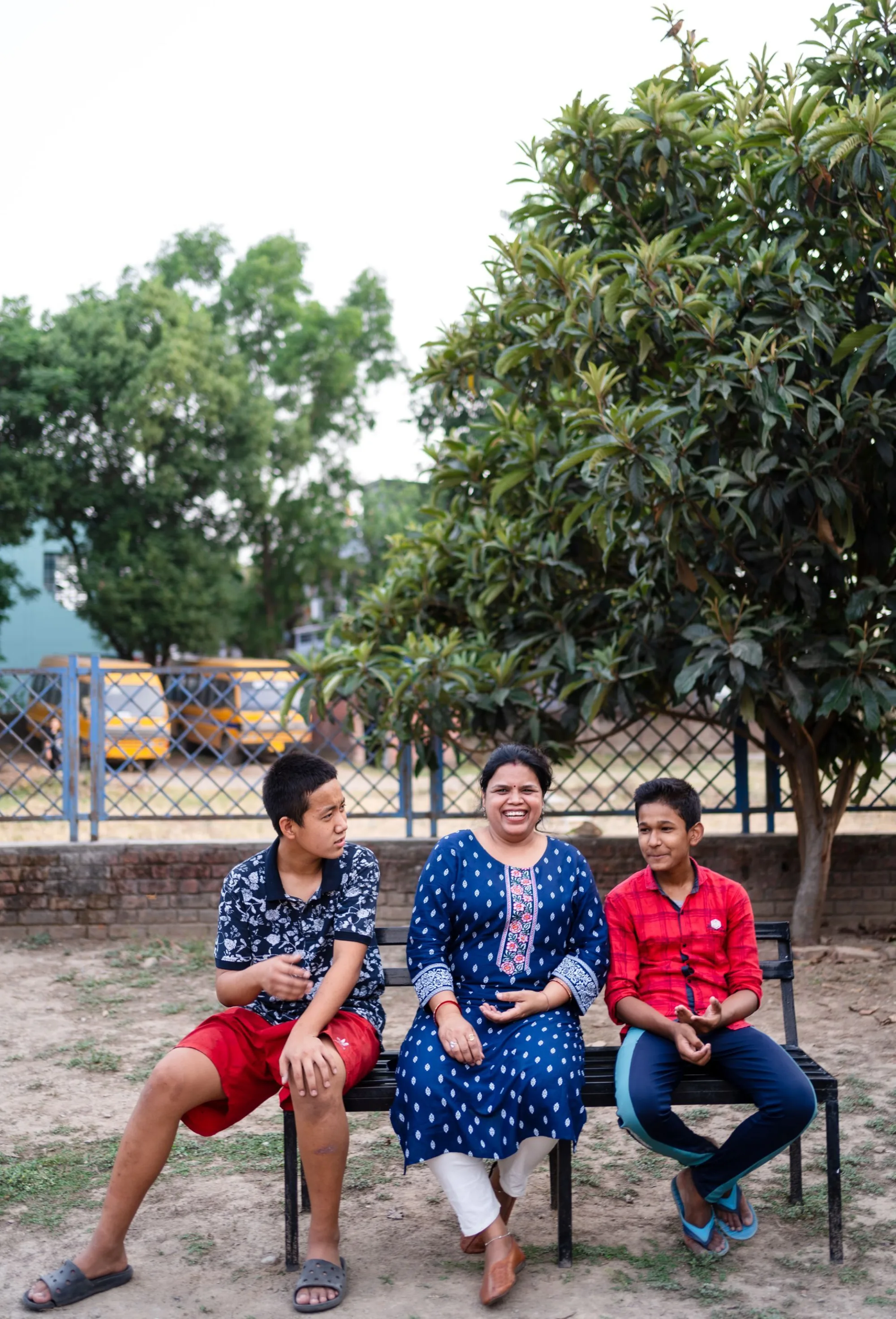 Two Boys sitting n a bench with their Housemother between them at Pestalozzi India