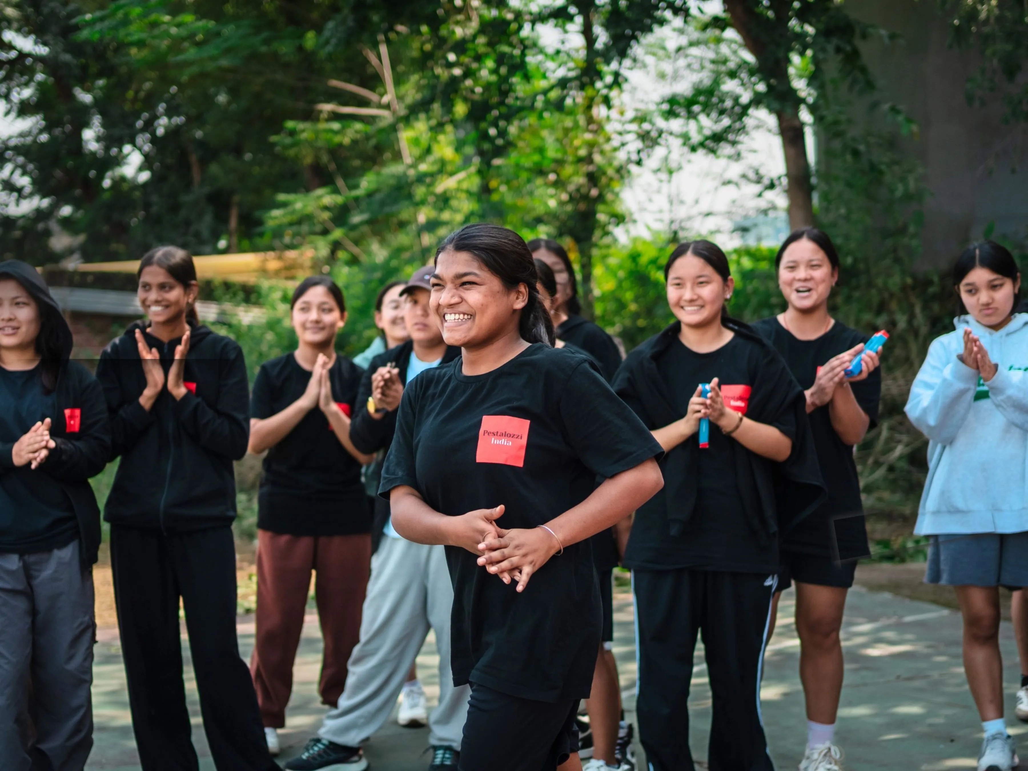 Image of girls supporting one another, clapping, smiling, cheering at Pestalozzi India.