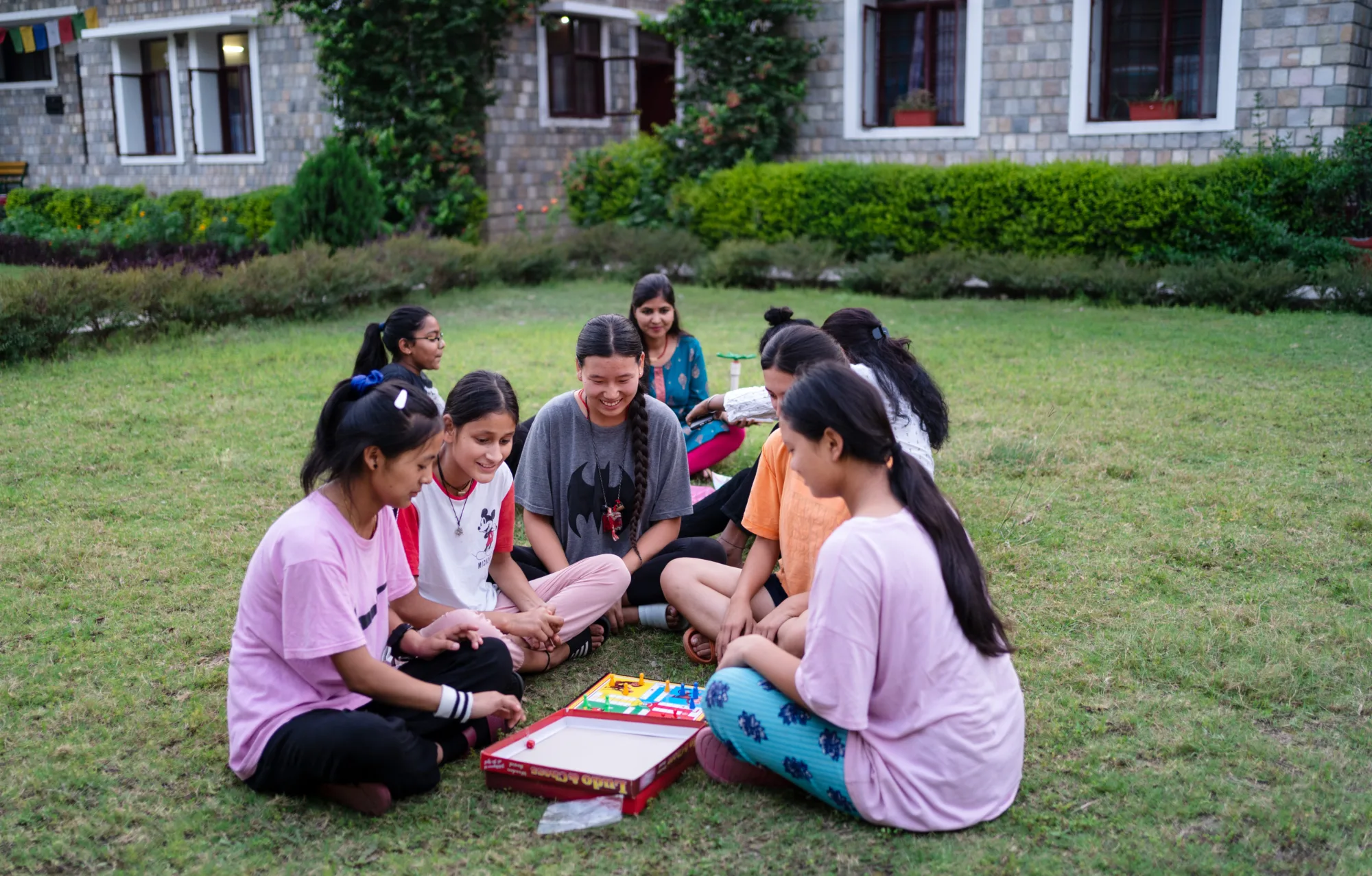 Group of girls of Pestalozzi International India in an outdoor art class, sitting on the lawn.