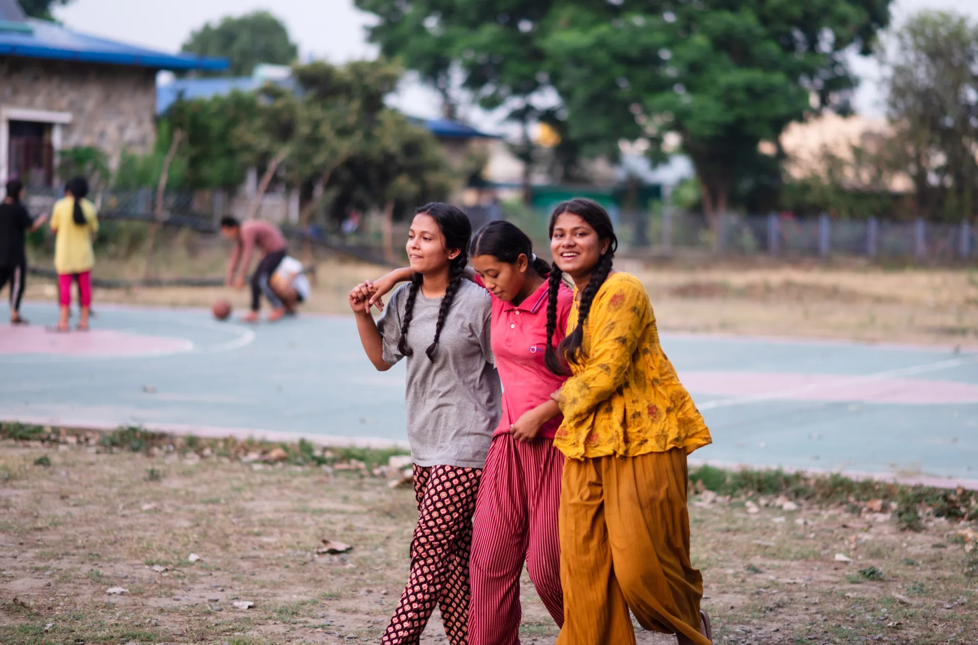Three Indian girls from Pestalozzi International, laughing and hugging each other