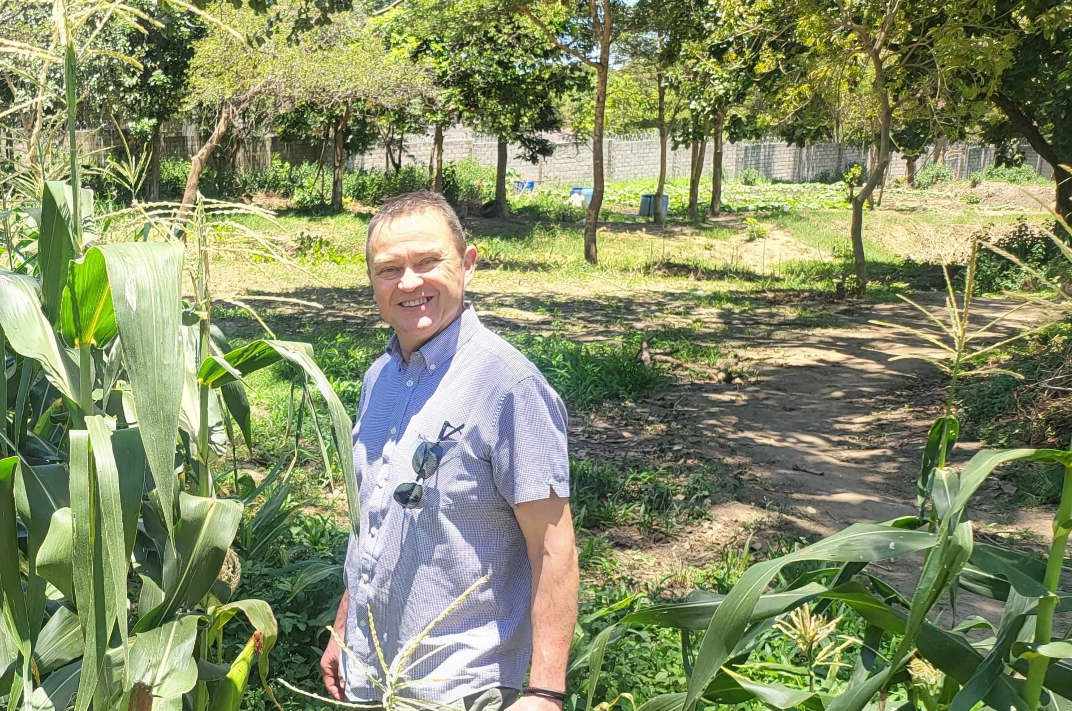 Pestalozzi International COO Eddie West-Burnham standing in a corn field at Lusaka Campus in Zambia.