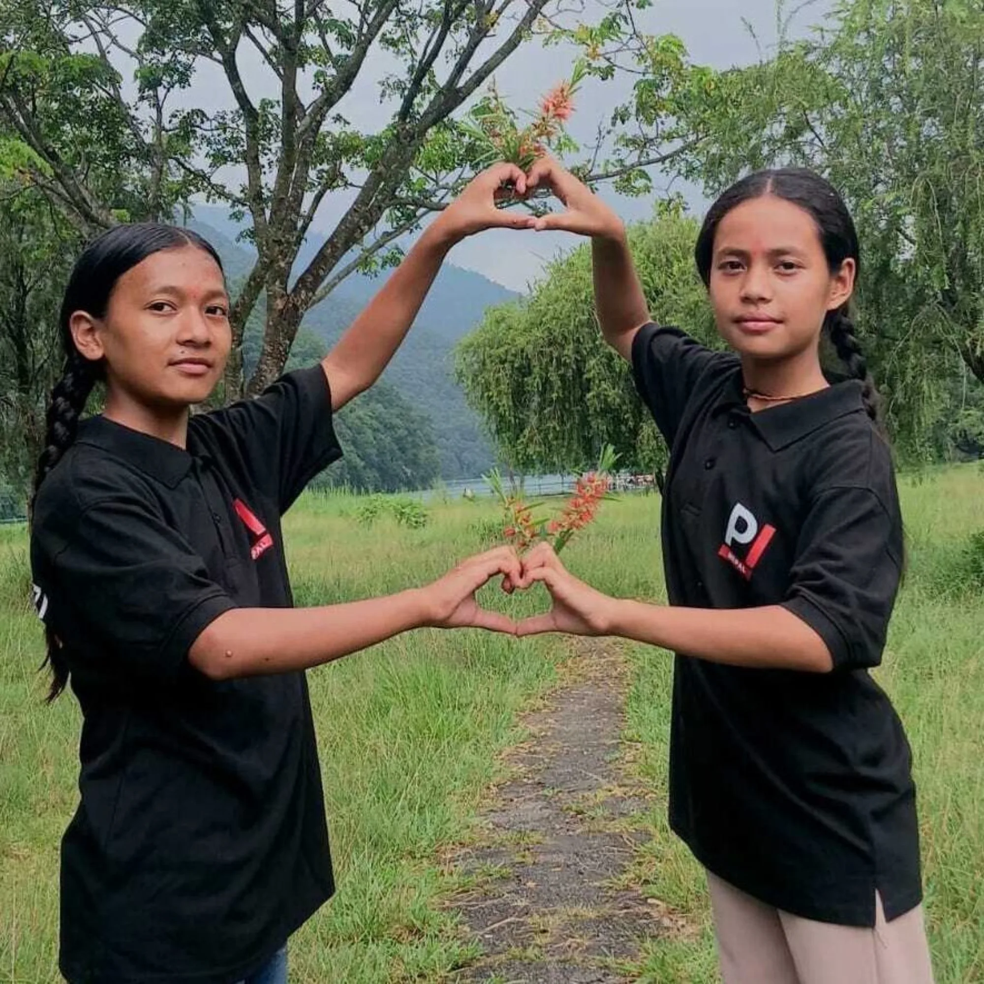 Two female students from Nepal joining hands to create two heart shapes