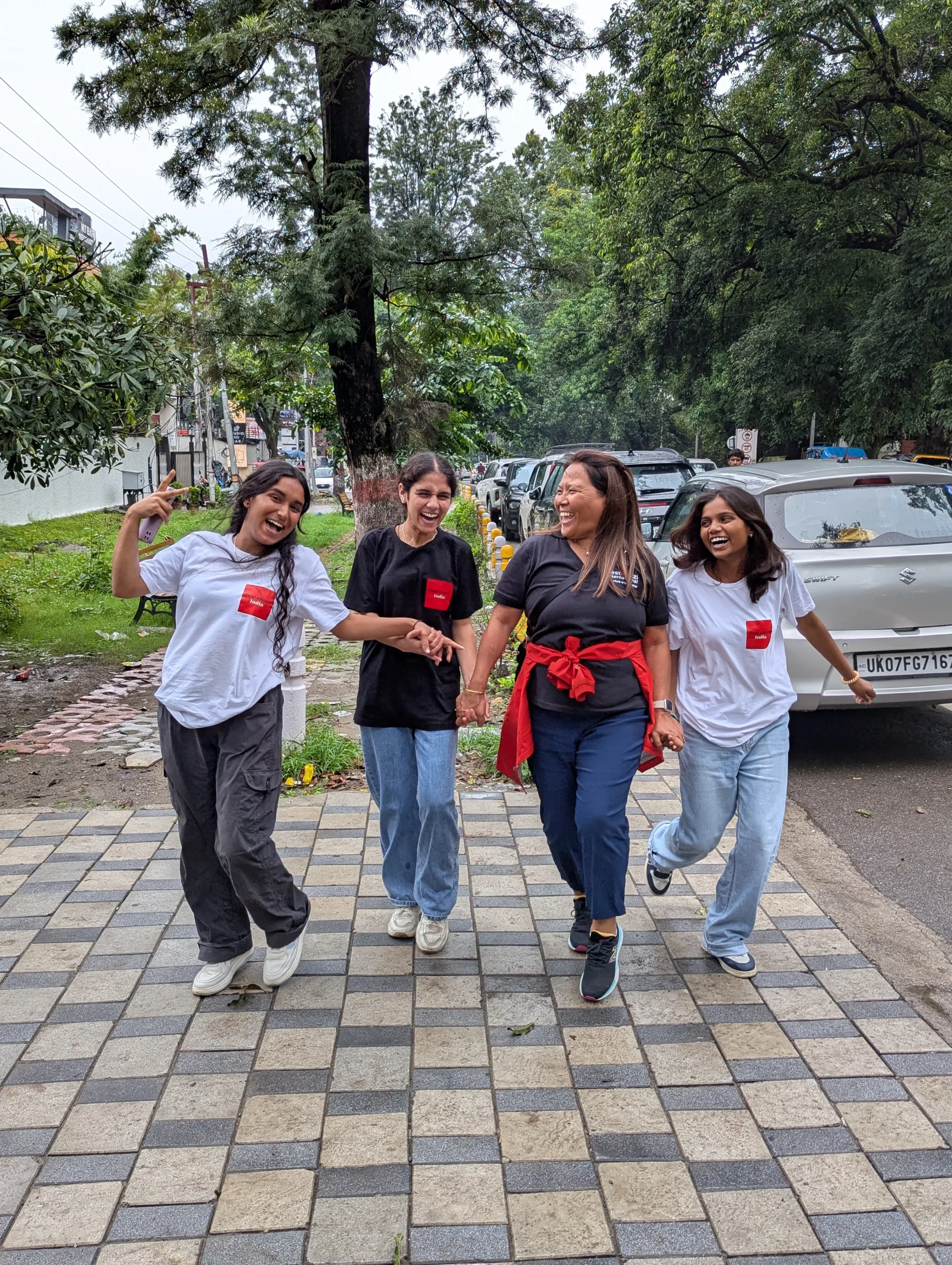 Group of two female students jumping for joy with the Director of our India campus Cheme