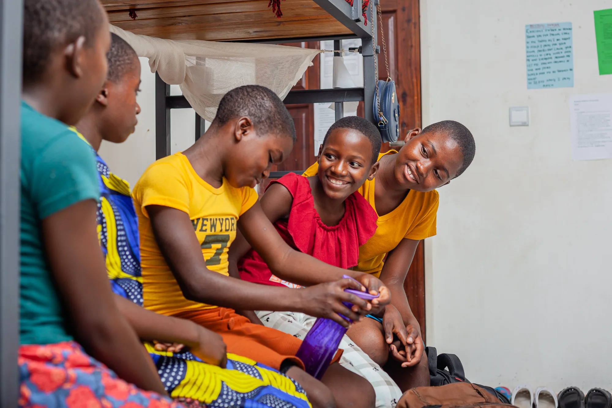 Five children sitting on lower bed of a bunk bed chatting to each other
